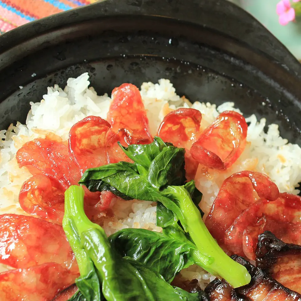 Claypot rice — lap cheong and greens over scorched rice in a black clay pot